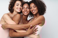 Preview: Three Smiling Young Women Embrace in Studio