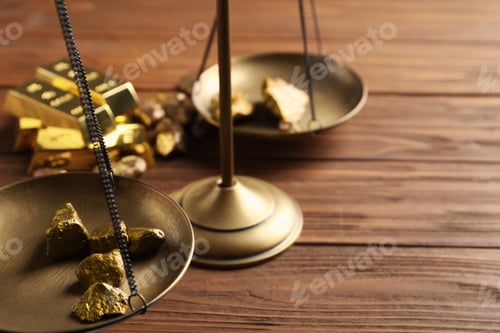 Preview: Scale pan with gold lumps on wooden table, closeup. Space for text