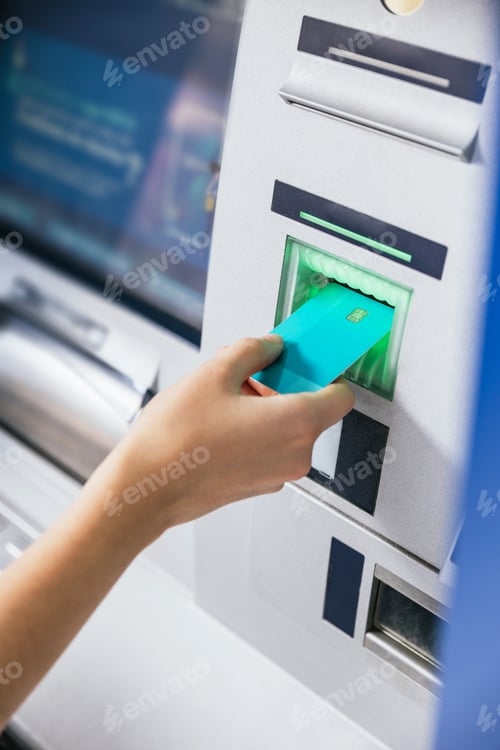 Preview: Close-up of a young woman's hand inserting a credit card into an ATM bank machine