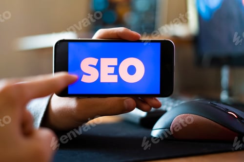 Preview: young male worker holding a smartphone with SEO text design in the office, search engine