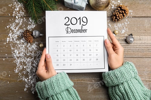 Preview: Woman with paper calendar at wooden table, top view