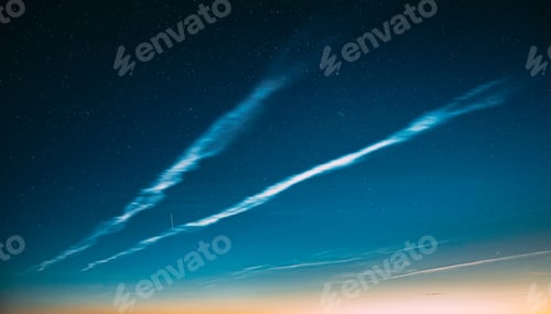 Preview: Night Starry Sky And Noctilucent Clouds Above Summer Meadow Landscape. Glowing Stars And Night