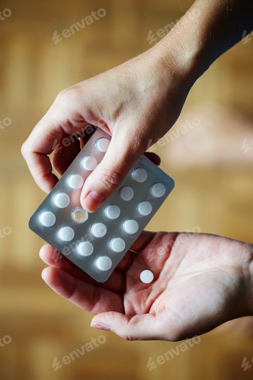 Preview: Young woman taking medication from blister pack, close-up