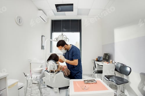 Preview: Young Male Dentist Examining Female Patient in Dental Office