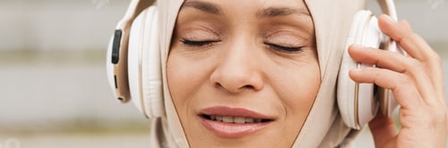 Preview: Middle eastern woman in hijab listening music with wireless headphones