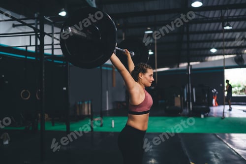Preview: Strong female athlete checking body strength during weightlifting workout in sportive studio,
