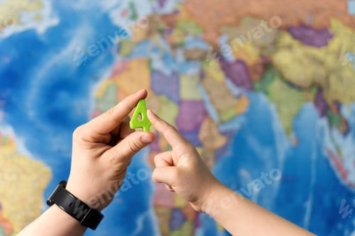 Preview: Adult And Child Hands Holding Numbers Plastic Toy On The World Political Map Background. Travel