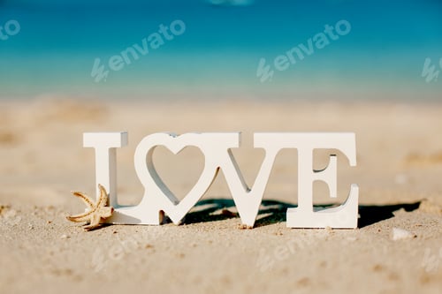 Preview: Wooden letters love on a sandy beach overlooking the blue sea