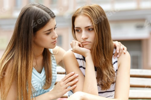 Preview: Attractive girl comforting upset friend, while sitting on bench