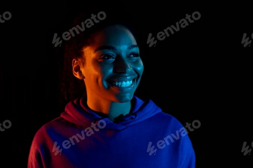 Preview: Portrait of young african american woman posing and smiling isolated on dark background in