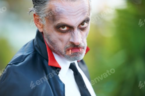 Preview: Mature man dressed up as Dracula for Halloween, scowling at the camera