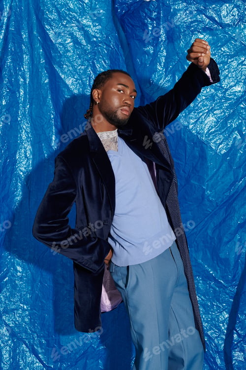 Preview: Handsome young man striking a confident pose against a vibrant blue backdrop