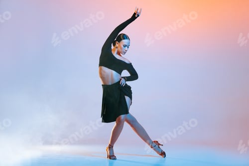 Preview: Stylish female dancer in black outfit posing in Latin dance move on vibrant gradient studio