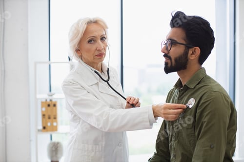 Preview: Serious bearded man visiting family doctor for examination in general practice.