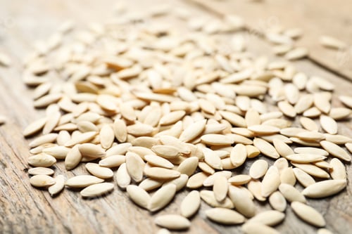 Preview: Raw cucumber seeds on wooden background, closeup. Vegetable planting