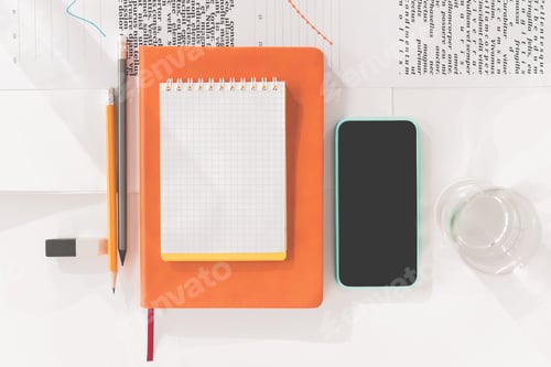 Preview: Top view of smartphone with blank screen, notebooks and pencils at workplace