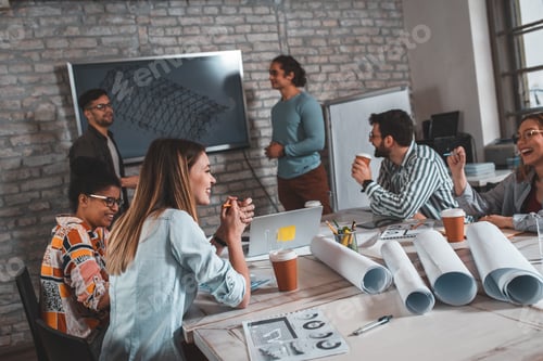 Preview: Group of modern business people in casual wear discussing architectural designs.