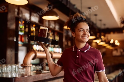 Preview: Happy waitress serving drinks in a bar.