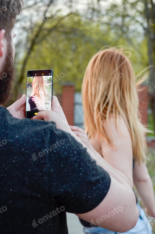 Preview: the guy takes a picture of his girlfriend on the phone. couple in love