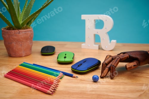 Preview: Computer mouse with multicolored pencils, articulated wooden hand, and aloe plant