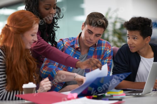 Preview: Four young female and male college students teamworking at desk