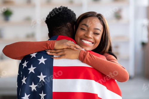 Preview: Independence Day. Happy Black Wife Embracing Husband Wrapped In American Flag