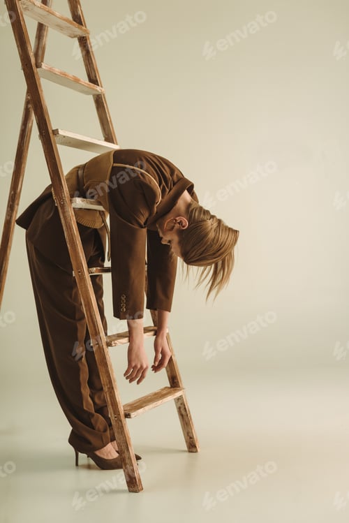 Preview: fashionable woman in vintage style posing near wooden ladder on beige