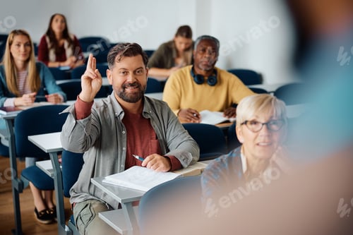 Preview: Mature man raising hand to ask a question while attending a class in lecture hall.