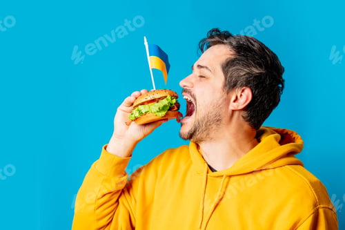 Preview: white guy in yellow hoodie with hamburger and Ukrainian flag on blue background