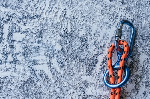 Preview: Isolated photo of climbing equipment. Part of carabiner lying on the white and grey colored surface