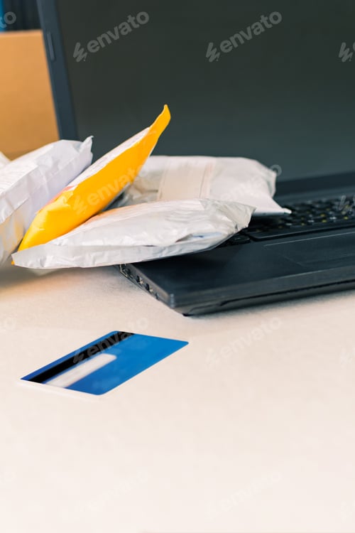 Preview: Vertical shot of delivered packages with a credit card and laptop keyboard