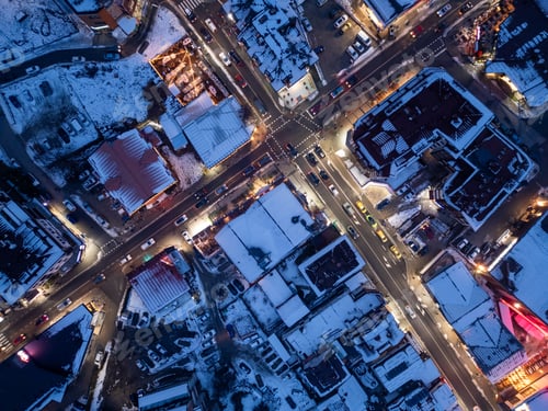 Preview: Snowy urban intersection at dusk with streetlights illuminating the streets and rooftops in a winter