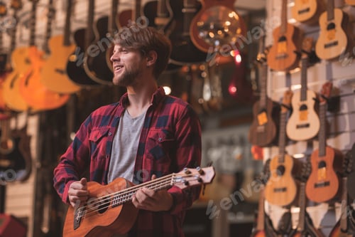 Preview: Smiling musician with a ukulele in a music store