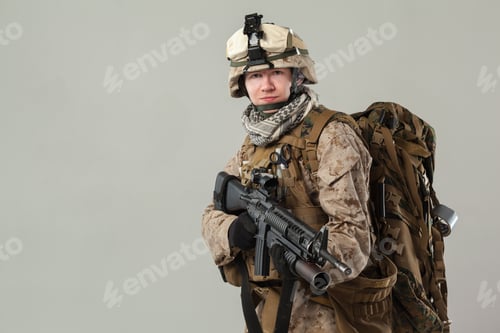 Preview: Soldier in military gear stands ready with a weapon and backpack in a studio setting