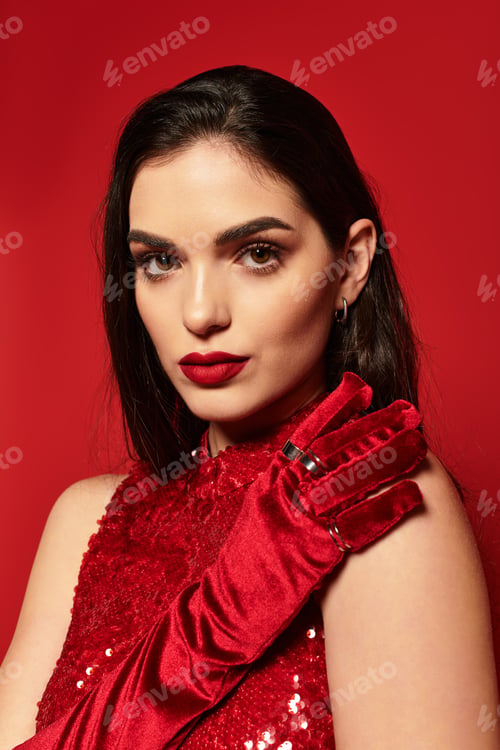 Preview: Striking beauty in a glamorous studio setting with bold red lips and elegant attire