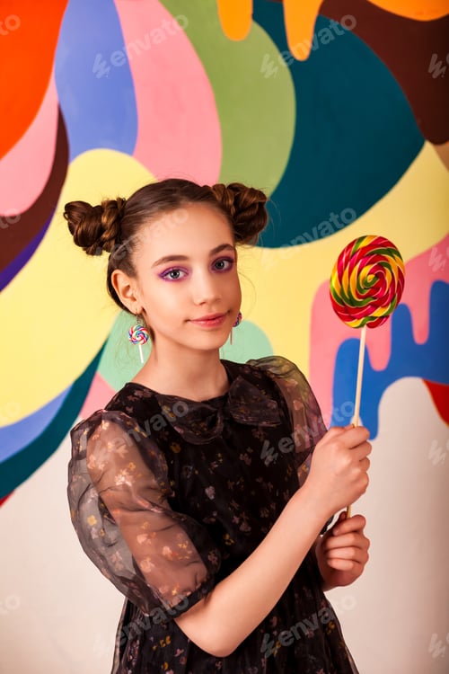 Preview: Charming cover child girl with round lollipop at colorful wall, looking at camera
