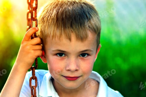 Preview: Portrait of a little smiling boy with golden blonde straw hair in sunny summer day on green blurred