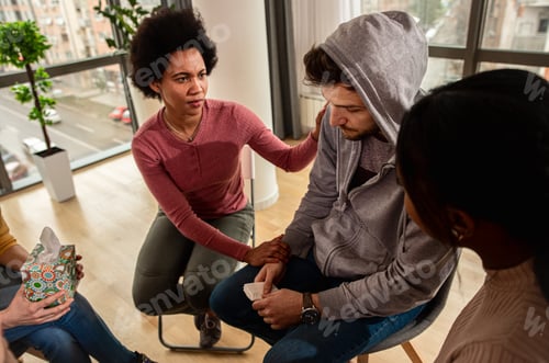 Preview: Diverse group of people sitting in circle in group therapy session.