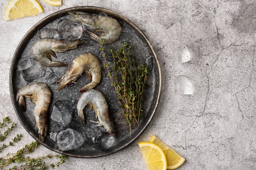Preview: Plate with shrimps, raw prawns with lemon slices, ice cubes and thyme.