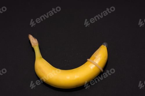 Preview: Banana with Condom on black background. Sexual Health and Education Concept