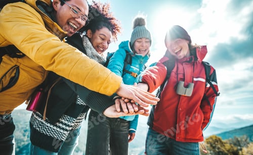 Preview: Multiracial happy hikers stacking hands outside