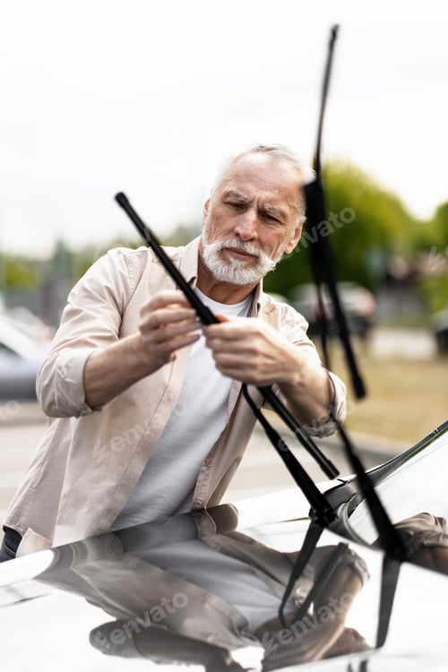 Senior Man Changing Car Windshield Wipers Outdoors