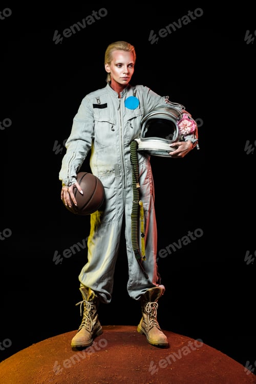 Preview: cosmonaut in spacesuit holding basketball ball and helmet with flower while standing on red planet