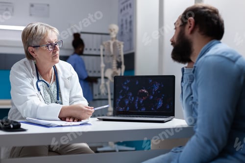 Preview: Doctor explaining coronavirus bacteria illustration on laptop to man in cabinet