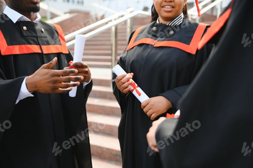 Preview: group of happy international students in mortar boards and bachelor gowns with diplomas
