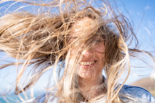 Preview: Closeup of young woman face covered with flying hair in windy day