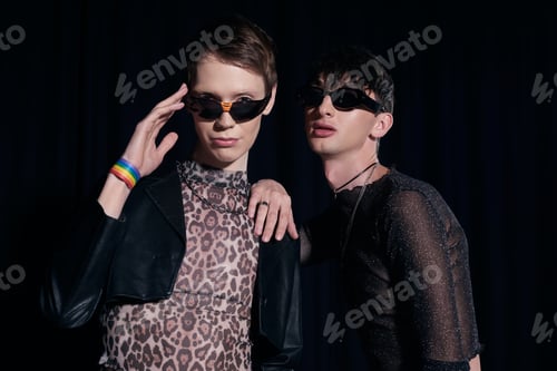 Preview: Portrait of fashionable queer persons in sunglasses and party outfits posing and looking at camera