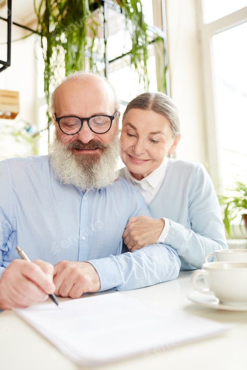 Preview: Affectionate Senior Couple Signing Documents at Home