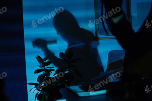 Preview: Silhouette of Young Adult Man Stealing in Office at Nighttime