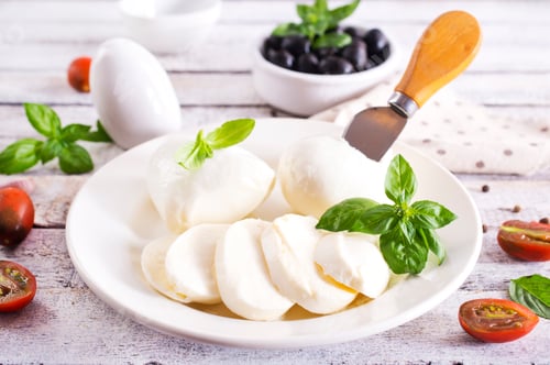 Preview: Large ball of mozzarella on white plate topped with herb oil